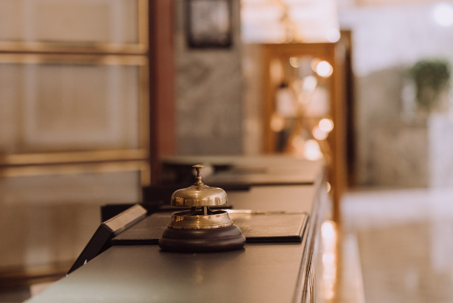 Close-up van een servicebel op een hotelreceptiebalie, symboliserend gastvrijheidsdiensten die elektronisch beheerd kunnen worden via Redforts-software.